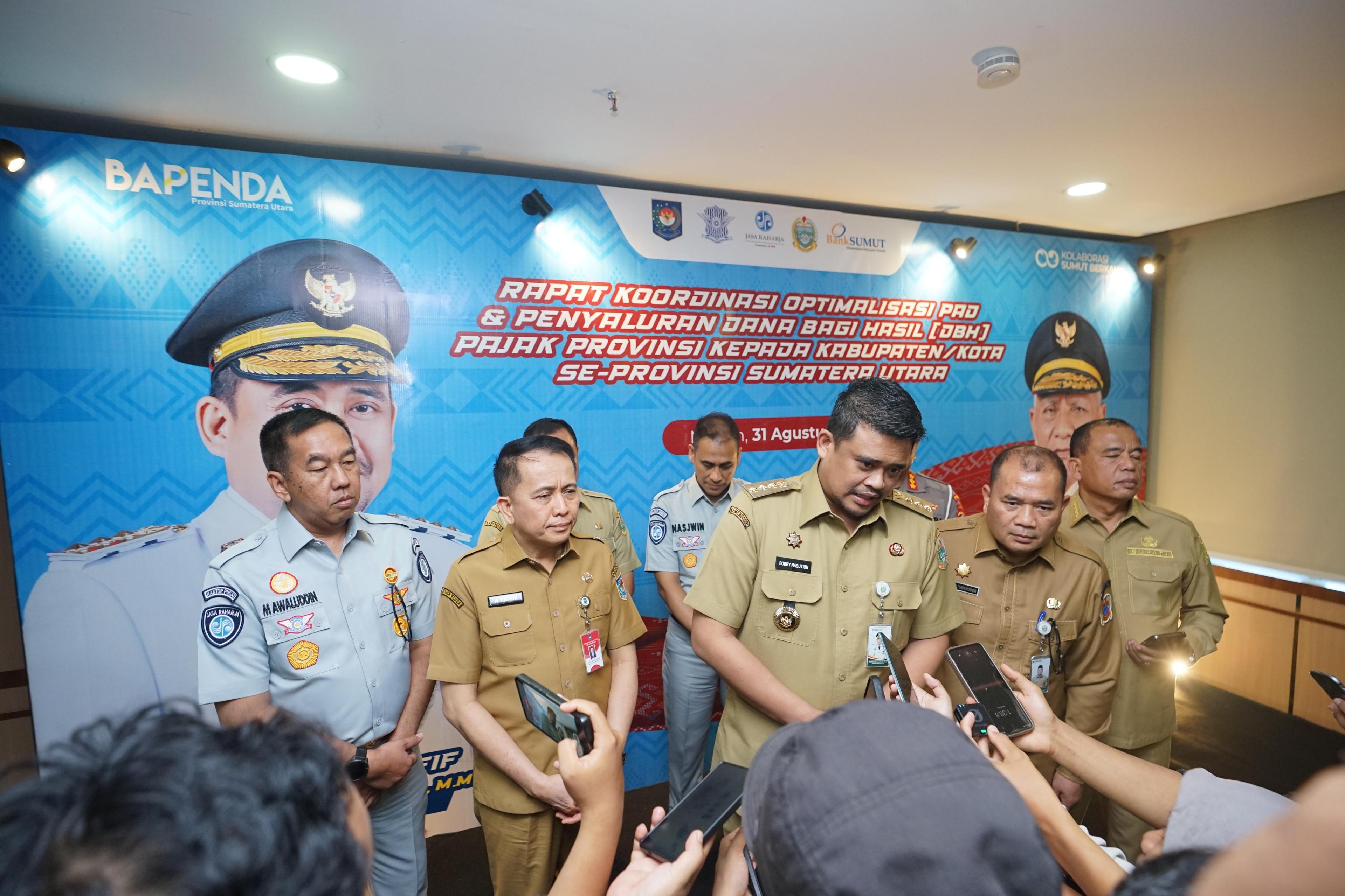MEDAN — PT Jasa Raharja (persero) terus mendorong penguatan kolaborasi Tim Pembina Samsat Nasional untuk meningkatkan kepatuhan masyarakat, memperbaiki validitas data kendaraan, dan mengoptimalkan Pendapatan Asli Daerah (PAD). Hal itu disampaikan Direktur Utama Jasa Raharja, Muhammad Awaluddin, dalam Rapat Koordinasi Optimalisasi Pendapatan Asli Daerah dan Penyaluran Dana Bagi Hasil Pajak Provinsi se-Sumatera Utara, di Aula Raja Inal Siregar, Kantor Gubernur Sumatera Utara, Medan, Senin (31/8/2026).
Rapat dipimpin Gubernur Sumatera Utara, Bobby Nasution dan dihadiri oleh Direktur Jenderal Perhubungan Darat sekaligus Komisaris Utama PT Jasa Raharja, Irjen Pol. (Purn.) Aan Suhanan, Dirjen Bina Keuangan Daerah Kementerian Dalam Negeri, Agus Fatoni, Direktur Operasional Jasa Raharja, Ariyandi, Kasubdit STNK Ditregident Korlantas Polri, Kombes Pol. Dedy Suhartono, serta Kepala Bidang Evaluasi Pendapatan Bapenda Sumatera Utara, Sofyan Romi Wandy. Agenda tersebut juga diikuti jajaran Pemerintah Provinsi Sumatera Utara dan pemerintah kabupaten/kota se-Sumatera Utara.
Direktur Utama Jasa Raharja, Muhammad Awaluddin menyampaikan, optimalisasi penerimaan pajak kendaraan bermotor membutuhkan kerja bersama seluruh pemangku kepentingan. Kolaborasi tersebut perlu diarahkan pada pembenahan data, perluasan akses pelayanan, dan peningkatan pemahaman masyarakat mengenai kewajiban pajak kendaraan. “Tentunya, membangun pelayanan yang mudah, transparan, dan dipercaya masyarakat adalah salah satu upaya kita bersama untuk mengoptimalkan pendapatan,” ujarnya.
Menurut Awaluddin, Jasa Raharja siap memperkuat sinergi dengan Bapenda dan Kepolisian melalui validasi data kendaraan, pengembangan kanal pelayanan, serta edukasi yang mendorong kepatuhan masyarakat. Ia mengatakan, kepatuhan masyarakat dalam membayar Pajak Kendaraan Bermotor (PKB) memiliki arti penting bagi pembangunan daerah. Sementara itu, pembayaran Sumbangan Wajib Dana Kecelakaan Lalu Lintas Jalan (SWDKLLJ) berperan dalam mendukung keberlanjutan perlindungan dasar bagi korban kecelakaan lalu lintas. “Ketika masyarakat memenuhi
kewajibannya, manfaatnya kembali kepada masyarakat melalui pembangunan daerah dan perlindungan dasar bagi korban kecelakaan,” tambahnya.
Dalam arahannya, Bobby Nasution menyoroti pentingnya pemerataan pembangunan daerah melalui kebijakan opsen pajak. Melalui skema tersebut, bagian penerimaan PKB disalurkan langsung ke kas pemerintah kabupaten dan kota berdasarkan potensi kendaraan di wilayah masing-masing.
Bobby juga mengusulkan agar kemungkinan penyesuaian tarif PKB berdasarkan wilayah, dikaji. Opsi tersebut dinilai dapat mendorong masyarakat membeli dan mendaftarkan kendaraannya di daerah asal. Dengan demikian, potensi penerimaan pajak kendaraan tidak hanya terkonsentrasi di Kota Medan dan Kabupaten Deli Serdang.
“Kalau dahulu dibagi ke daerah lain, tetapi sekarang itu sesuai jumlahnya. Makanya bagaimana jika di daerah tertentu untuk kendaraan itu, pajaknya kita rendahkan. “Sehingga, tidak semua orang membeli mobil ke Medan, misalnya. Dengan demikian, potensi penerimaan dari sektor pajak kendaraan dapat lebih merata antardaerah,” ujarnya.
Berdasarkan data Bapenda Sumatera Utara hingga Agustus 2026, realisasi penerimaan pajak daerah mencapai 55,41 persen atau sekitar Rp3,86 triliun dari target Rp6,96 triliun. Bobby mengapresiasi capaian tersebut. Namun, ia meminta seluruh jajaran pemerintah daerah mempercepat pencapaian target penerimaan hingga akhir tahun.
Tingkat Kepatuhan Masyarakat
Dalam kesempatan yang sama, Aan Suhanan menyoroti tingkat kepatuhan pembayaran PKB di Sumatera Utara yang masih berada di angka 36,89 persen. Angka tersebut berada di bawah rata-rata nasional sebesar 47,72 persen. “Ini merupakan tantangan besar mengingat PKB dan BBNKB menyumbang hampir 50% atau sekitar Rp2,9 triliun dari total PAD Sumut,” ujarnya. Aan juga menekankan pentingnya rekonsiliasi dan pemutakhiran sekitar 189.000 data kendaraan. Sebagian data tersebut berkaitan dengan kendaraan yang sudah tidak beroperasi, rusak, atau berstatus barang bukti di kantor kepolisian. “Pemutakhiran data ini sangat vital agar database menjadi valid untuk mengevaluasi kinerja secara akurat,” tambahnya.
Aan meminta tiga unsur Tim Pembina Samsat, yakni Bapenda, Kepolisian, dan Jasa Raharja, memperkuat konsolidasi dalam tiga hingga empat bulan tersisa menjelang akhir tahun. Upaya meningkatkan kepatuhan juga perlu dilakukan melalui pendekatan yang humanis dan persuasif. Sementara itu, Kasubdit STNK Ditregident Korlantas Polri, Kombes Pol. Dedy Suhartono, menekankan pentingnya integrasi pelayanan Samsat yang lebih solid, responsif, dan sesuai dengan kebutuhan masyarakat. Sejumlah langkah yang didorong meliputi perluasan layanan Samsat Keliling hingga wilayah yang sulit dijangkau, penyediaan kanal pembayaran yang lebih fleksibel, serta edukasi mengenai pentingnya balik nama kendaraan.
Dedy juga mendorong interkoneksi basis data antara Bapenda, Kepolisian, dan Jasa Raharja. Rekonsiliasi data secara berkala dibutuhkan untuk memastikan legalitas dan akurasi data kendaraan maupun wajib pajak. “Aplikasi SIGNAL (Samsat Digital Nasional) didorong sebagai solusi transaksi elektronik utama masyarakat tanpa batasan waktu dan tempat,” ujarnya.
Adapun Agus Fatoni mengatakan, PAD merupakan salah satu indikator kemandirian fiskal daerah. Untuk meningkatkan penerimaan, pemerintah daerah didorong menjalankan lima strategi, yakni intensifikasi, ekstensifikasi, peningkatan kapasitas sumber daya manusia, digitalisasi, dan inovasi progresif. Agus juga memaparkan sejumlah alternatif pembiayaan kreatif. Alternatif tersebut mencakup optimalisasi PAD dan dana transfer daerah, revitalisasi BUMD dan BLUD, pemanfaatan aset daerah, pinjaman atau obligasi daerah, sukuk daerah, serta kerja sama pemerintah dengan badan usaha. Pilihan lainnya adalah pemanfaatan dana tanggung jawab sosial perusahaan dan kolaborasi dengan Baznas untuk mendukung program pengentasan kemiskinan.
“Kami memberikan apresiasi khusus dan mendorong replikasi serta standardisasi berbagai inovasi pelayanan Samsat yang telah dirintis di Sumatera Utara, seperti Samsat Drive-Thru hasil kolaborasi dengan Bank Sumut,” ungkap Agus.